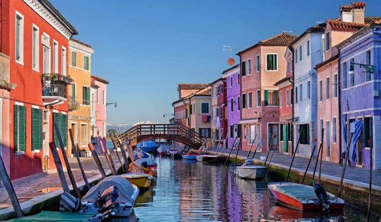 Colored buildings reflecting on the water in Burano, Italy.