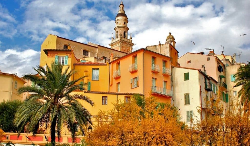 Gorgeous, colorful buildings under a cloudy sky with palm trees in Menton's Old Town. Gorgeous, colorful buildings under a cloudy sky with palm trees in Menton's Old Town.