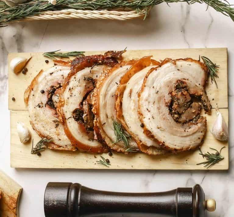 30 Traditional Italian Dishes to Try 8 Slices of porchetta surrounded by chopped rosemary and garlic cloves